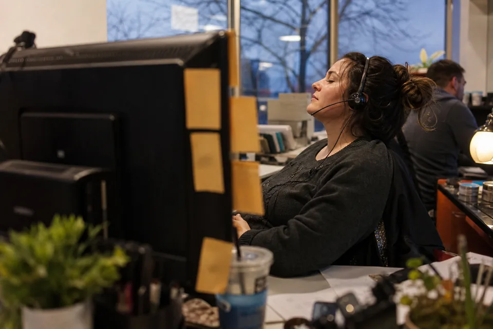 Sales development rep with a headset at her desk in a small sales office at dusk