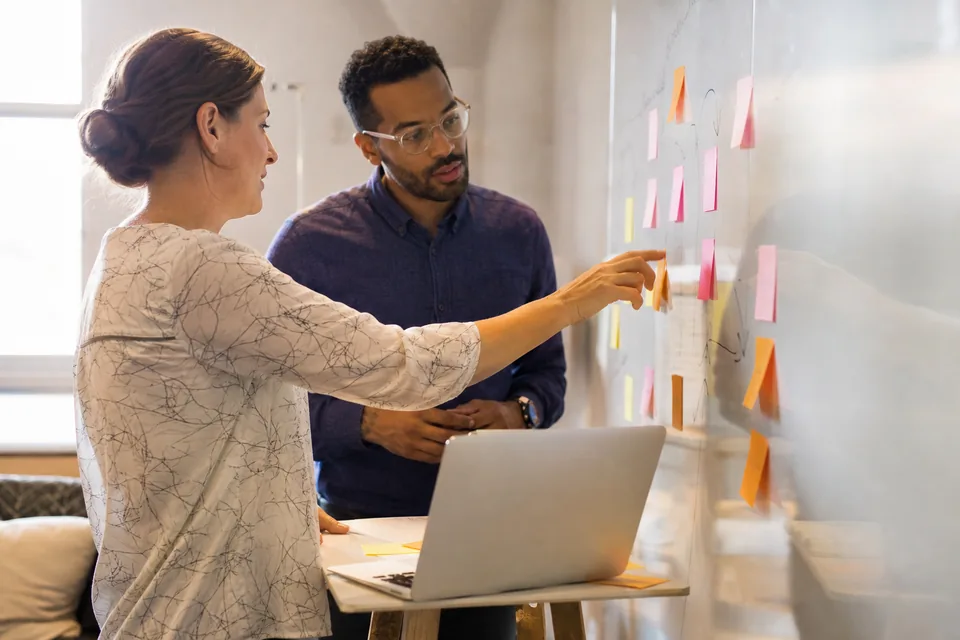 Two sales operations colleagues planning an outbound campaign at a whiteboard